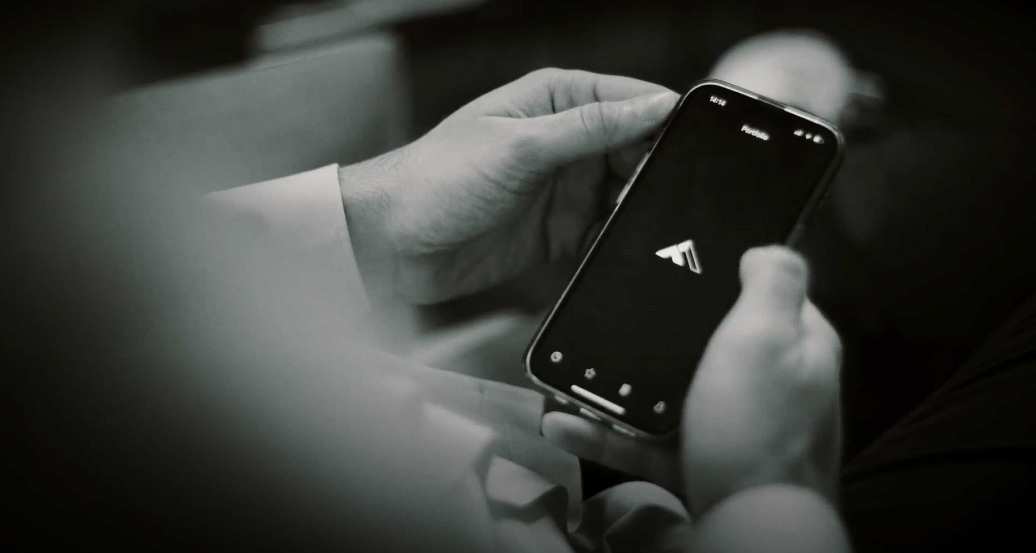 Blick über die Schulter eines Mannes, der Smartphone mit FINVIA-Logo in Händen hält. Bild in schwarz-weiß